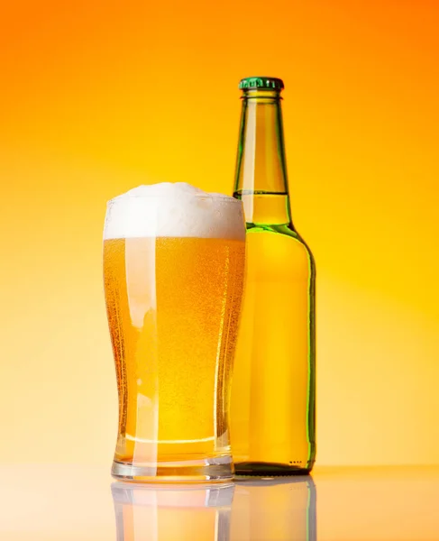 黄色の背景の前にラガービールとビールボトルとガラス スタジオショット — ストック写真