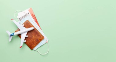 Seyahat ve tatil konsepti. Aksesuarlar ve eşyalar. Uçak biletleri ve yüz maskeleriyle pasaport yerine uçak oyuncağı. Üst görünüm düzlüğü kopyalama alanı ile yatıyordu