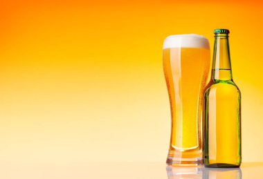 Bira şişesi ve bira, sarı arka planda bira. Kopyalama alanı ile stüdyonun görüntüsü