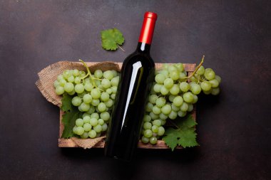 Kırmızı şarap şişesi ve tahta kutuda beyaz üzüm. Üst görünüm düzlüğü