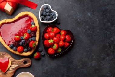 Kalp şeklinde tatlı kek, böğürtlen, kahve ve hediye kutusu. Sevgililer Günü tebrik kartı. Üst görünüm düzlüğü kopyalama alanı ile yatıyordu