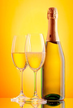 İki şampanya bardağı ve köpüklü şarap şişesi. Sarı arkaplan