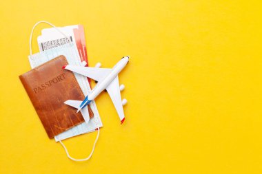 Seyahat ve tatil konsepti. Uçak oyuncağı, pasaport ve yüz maskesi. Aksesuarlar ve eşyalar. Üst görünüm düzlüğü kopyalama alanı ile yatıyordu