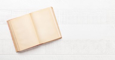 Beyaz ahşap masada boş sayfaları olan eski bir kitap. Üst görünüm düzlüğü kopyalama alanı ile yatıyordu