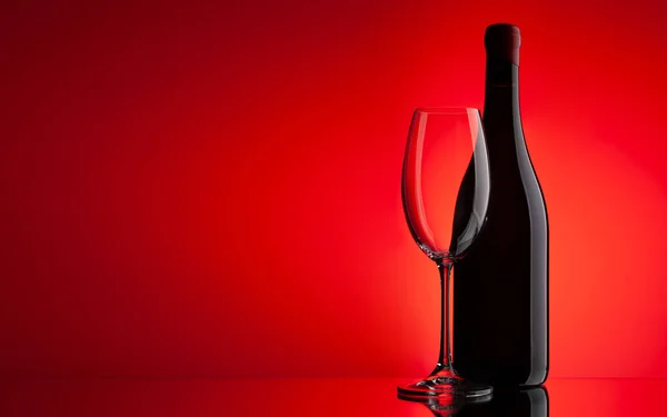 Rött Vin Glas Och Flaska Över Röd Bakgrund Med Kopieringsutrymme — Stockfoto