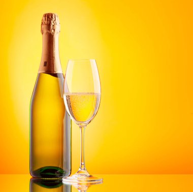 Şampanya bardağı ve köpüklü şarap şişesi. Kopyalama alanı olan sarı arkaplan