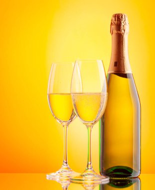 İki şampanya bardağı ve köpüklü şarap şişesi. Kopyalama alanı olan sarı arkaplan