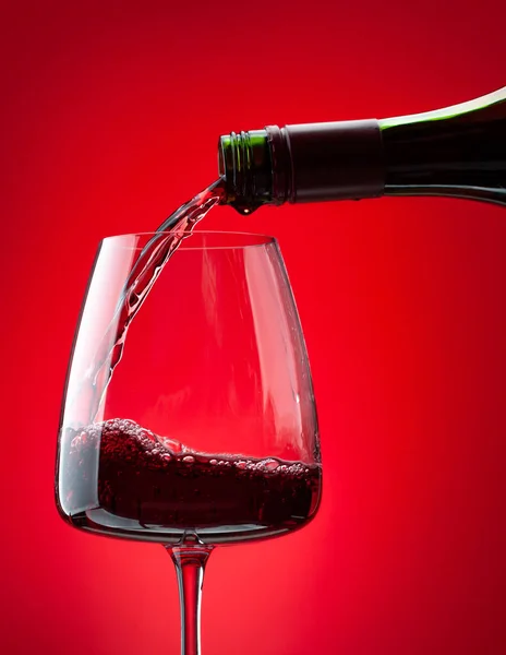Rotwein Der Aus Der Flasche Das Glas Über Rotem Hintergrund — Stockfoto