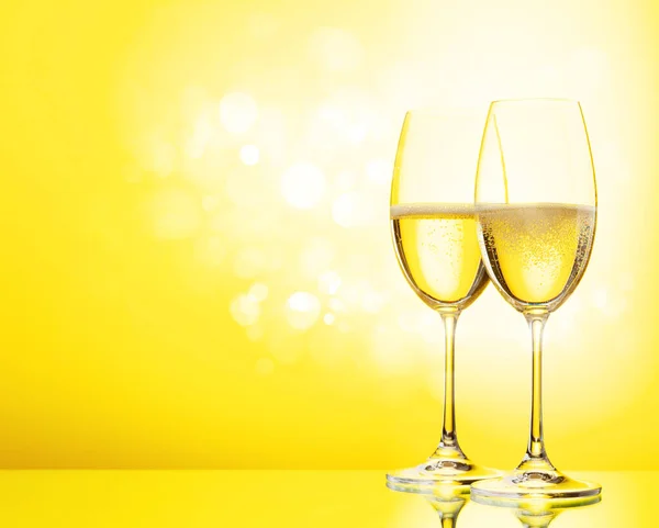 シャンパングラス2本とスパークリングワインボトル 黄色の背景に — ストック写真