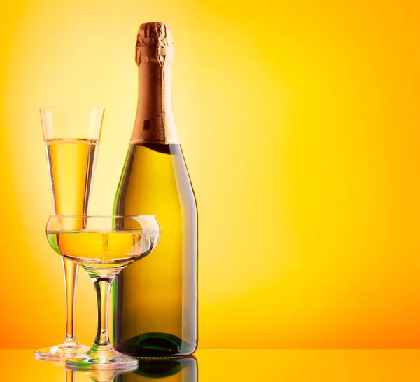 两杯香槟和一个闪闪发光的酒瓶带有复制空间的黄色背景 — 图库照片