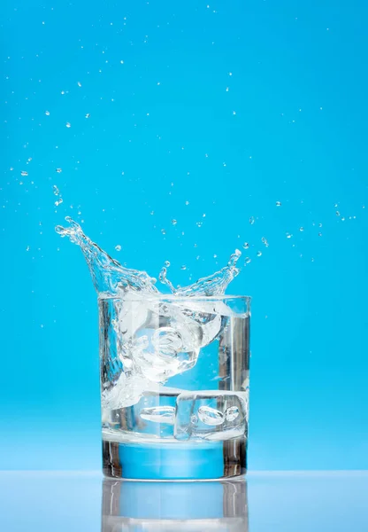 Vidro Água Com Cubos Gelo Respingo Sobre Fundo Azul Com — Fotografia de Stock