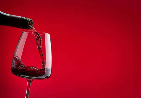 Rött Vin Häller Från Flaska Glas Över Röd Bakgrund Med — Stockfoto