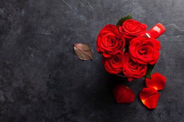 Kahve fincanında gül çiçekleri ve taç yaprakları. Sevgililer Günü tebrik kartı. Selamlarınız için yer var. Üst görünüm düzlüğü