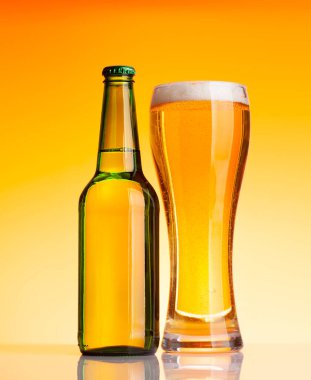 Bira şişesi ve bira, sarı arka planda bira. Stüdyo çekimi