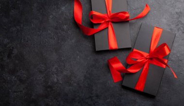 Üzerinde kırmızı kurdele olan iki siyah hediye kutusu. Üst görünüm düzlüğü kopyalama alanı ile yatıyordu