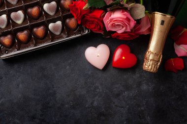 Şampanya şişesi, gül çiçekleri ve kalp şeklinde şeker. Sevgililer Günü tebrik kartı. İçi mumlarla dolu ve selamlarınız için yer var. Üst görünüm düzlüğü