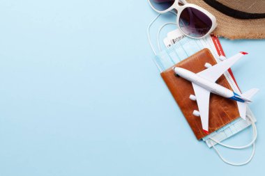 Seyahat ve tatil konsepti. Aksesuarlar ve eşyalar. Uçak biletleri ve yüz maskeleriyle pasaport yerine uçak oyuncağı. Üst görünüm düzlüğü kopyalama alanı ile yatıyordu