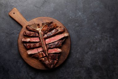 Izgara biftekli biftek. Bitki ve baharatla dilimlenmiş T-bone. Üst görünüm düzlüğü kopyalama alanı ile yatıyordu