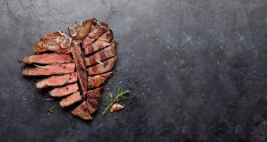 Izgara biftekli biftek. Bitki ve baharatla dilimlenmiş T-bone. Üst görünüm düzlüğü kopyalama alanı ile yatıyordu