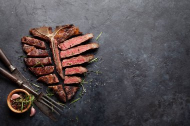 Izgara biftekli biftek. Bitki ve baharatla dilimlenmiş T-bone. Üst görünüm düzlüğü kopyalama alanı ile yatıyordu