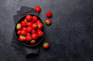 Taş masanın üzerinde olgun bir çilek kasesi. Üst görünüm düzlüğü kopyalama alanı ile yatıyordu