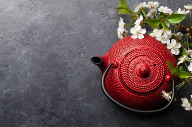 Çay demliğinde Japon çayı ve taş masada kiraz çiçeği. Üst görünüm düzlüğü kopyalama alanı ile yatıyordu