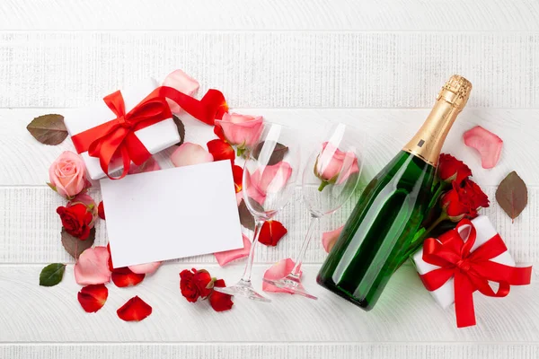 香槟瓶和玫瑰花瓣 情人节贺卡上有礼品盒和你的问候语空间 顶视图平铺 — 图库照片