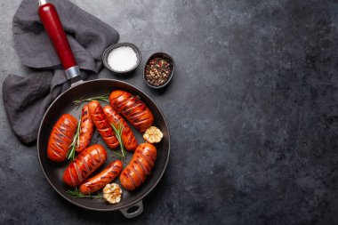 Kızartma tavasında ızgara sosis, sarımsak ve biberiyeli. Üst görünüm düzlüğü kopyalama alanı ile yatıyordu