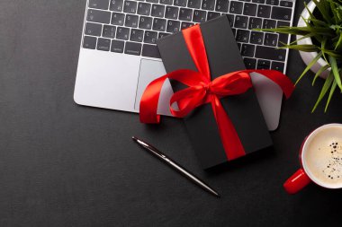 Ofis masasındaki dizüstü bilgisayarın üzerinde bir hediye kutusu. Tebrik etmek için en üstteki dairede yer var. Sevgililer Günü