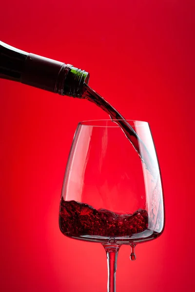 Vino Rosso Versando Bottiglia Vetro Sfondo Rosso — Foto Stock