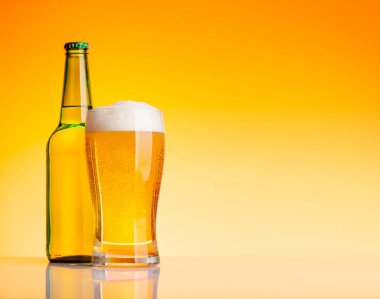 Bira şişesi ve bira, sarı arka planda bira. Kopyalama alanı ile stüdyonun görüntüsü