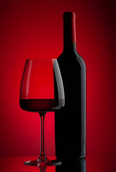 Κόκκινο Ποτήρι Κρασί Και Μπουκάλι Πάνω Από Κόκκινο Φόντο — Φωτογραφία Αρχείου