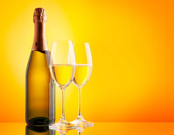 Två Champagneglas Och Mousserande Vinflaska Över Gul Bakgrund Med Kopieringsutrymme — Stockfoto