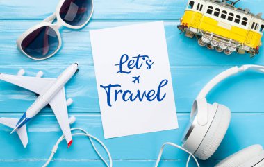 Seyahat ve tatil konsepti. Aksesuarlar ve eşyalar. Uçak ve tramvay oyuncakları, güneş gözlükleri ve kulaklıklar. Üst görünüm düzlüğü