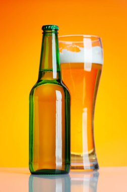 Bira şişesi ve bira, sarı arka planda bira. Stüdyo çekimi