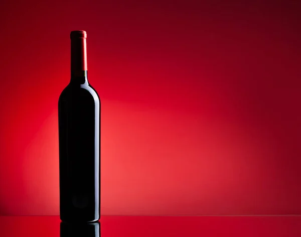 Röd Vinflaska Över Röd Bakgrund Med Kopieringsutrymme — Stockfoto