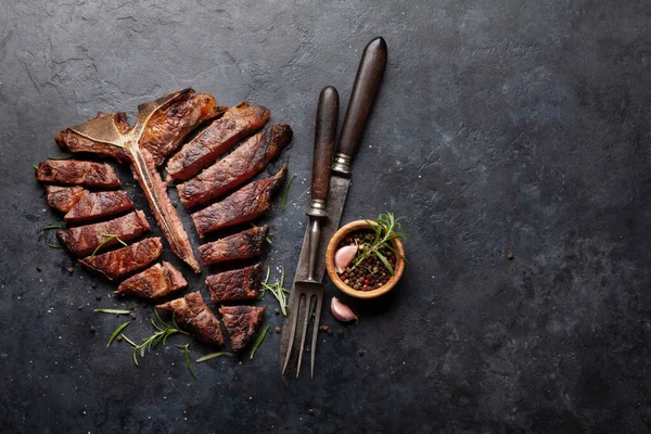 焼き肉のポーターハウスビーフステーキ ハーブやスパイスとスライスTボーン コピースペース付きのトップビューフラットレイ — ストック写真