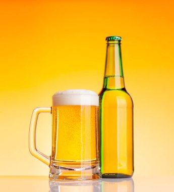 Bira şişesi ve bira, sarı arka planda bira. Stüdyo çekimi