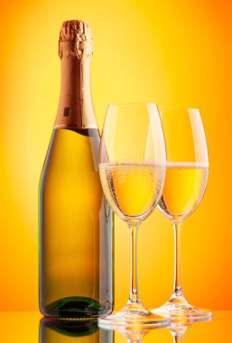 İki şampanya bardağı ve köpüklü şarap şişesi. Sarı arkaplan