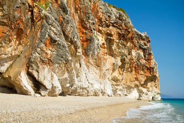 Praia ensolarada bonita cercada por alta parede do penhasco — Fotografia de Stock
