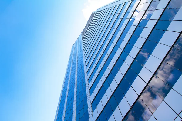 Bâtiment en verre bleu avec reflet ciel et nuages — Photo