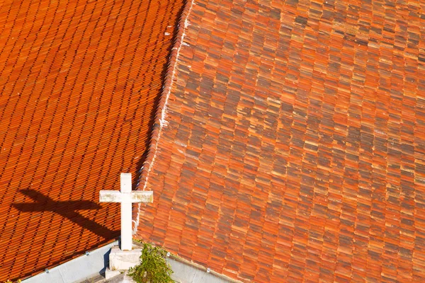 Cruz no telhado da igreja coberto com telhas laranja — Fotografia de Stock