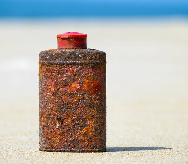 Old rusty metal bottle on the beach — Stock Photo, Image