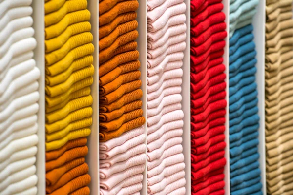 Pile ordinate di abbigliamento piegato sugli scaffali dei negozi — Foto Stock