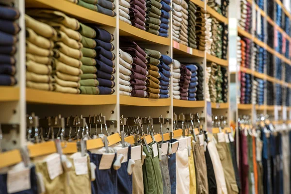 Pile ordinate di abbigliamento piegato sugli scaffali dei negozi — Foto Stock