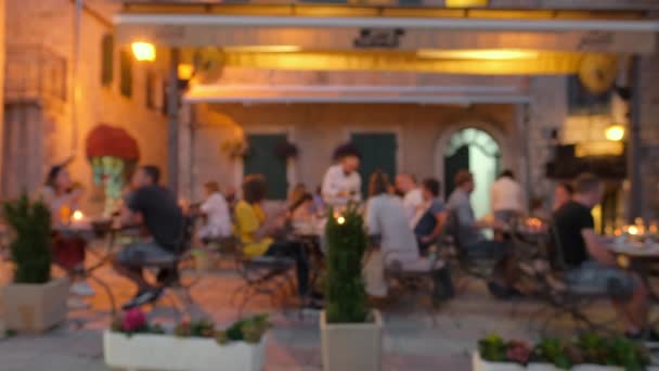 Oskärpa scen av människor som äter middag i utomhus restaurang på kvällen — Stockvideo