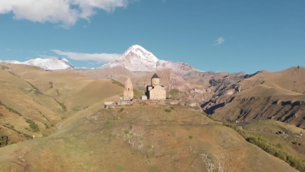 Iglesia de la Trinidad de Gergeti en Stepantsminda, montaña Kazbegi en el fondo, Georgia — Vídeos de Stock
