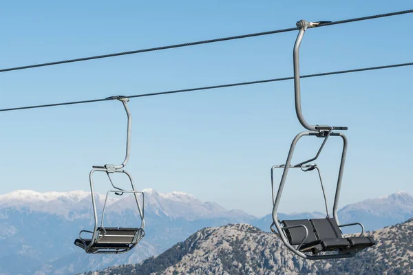 Cable car seats close-up with snow mountains at background. — Stock Photo, Image