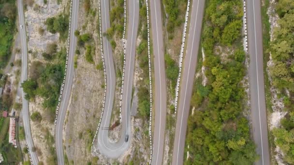 Vista aérea de cima para baixo da estrada serpentina de montanha com um carro em movimento — Vídeo de Stock