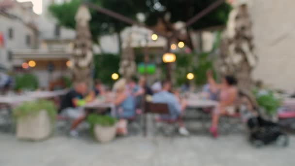 Escena desenfocada de personas cenando en un restaurante al aire libre por la noche — Vídeos de Stock